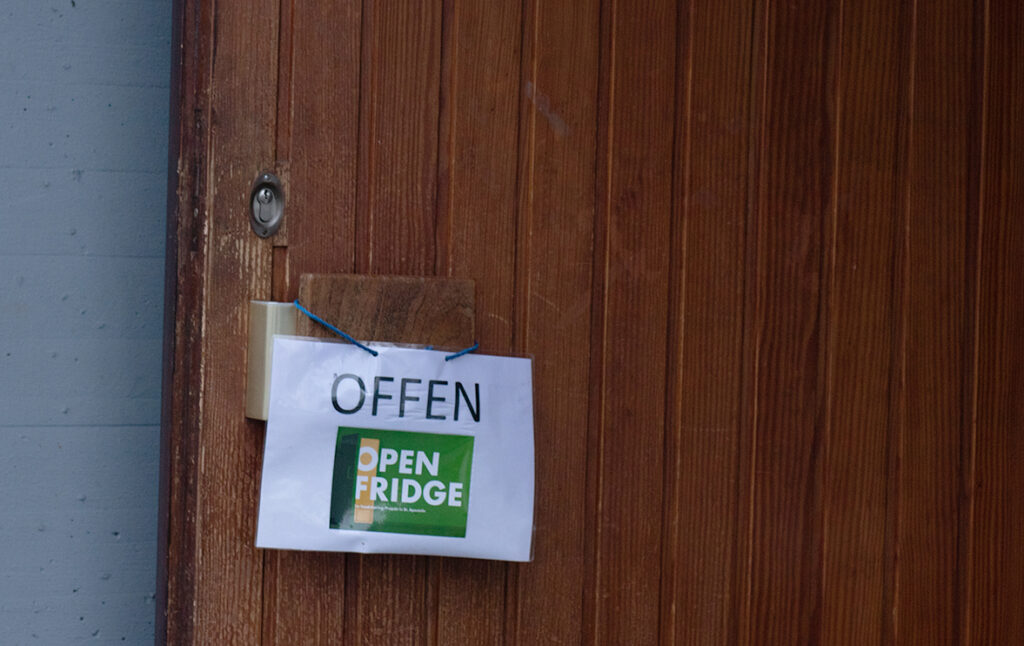 Der Open Fridge ist eine Initiative der Kirche St. Aposteln. Das Bild zeigt das Hiweisschild zum Open Fridge.