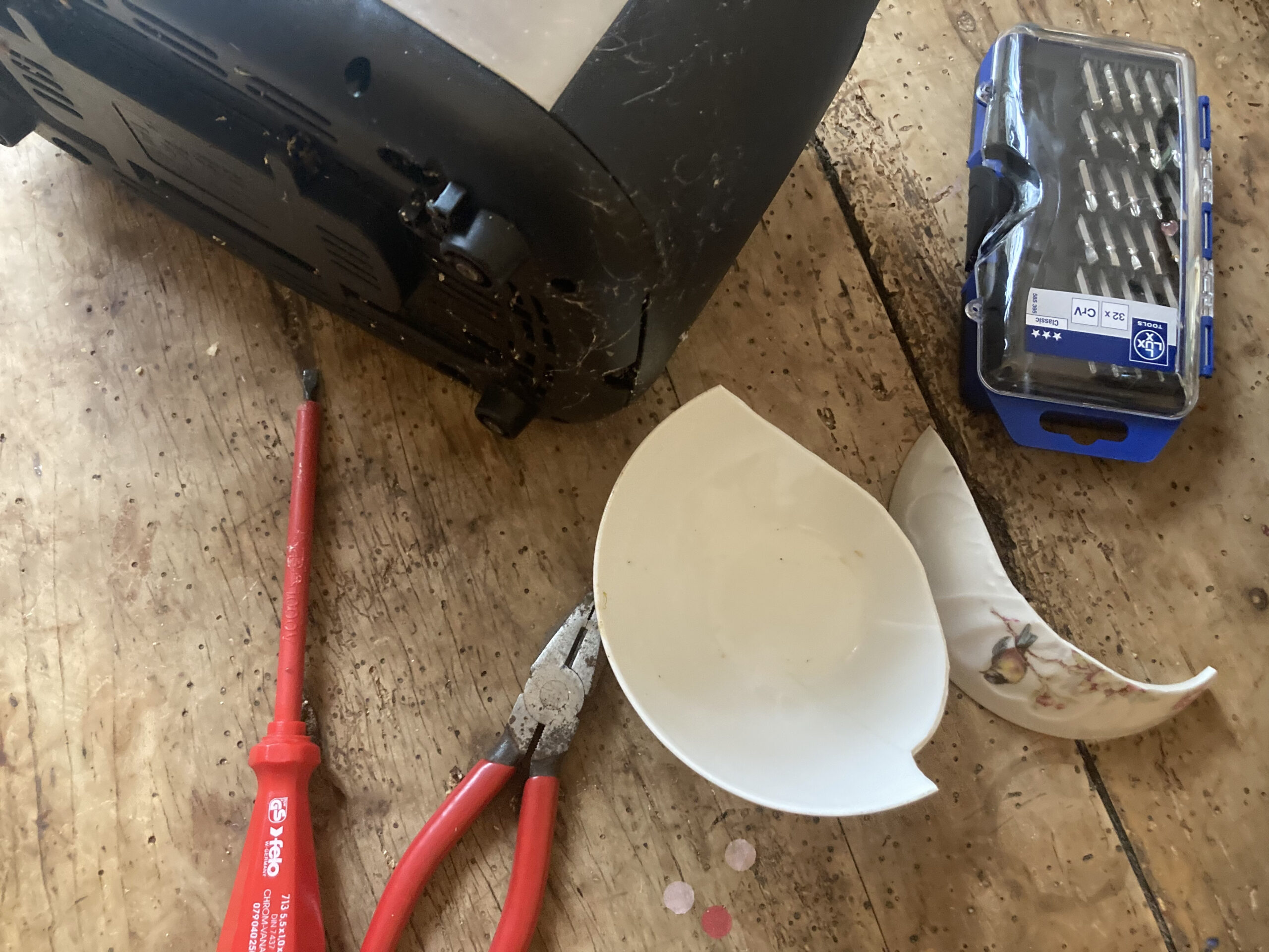 Das Bild zeigt einen Toaster, der auf einem Tisch auf der Seite liegt. Daneben liegt ein Schraubenzieher und eine Zange. Es ist ein Symbolbild für Repair Cafés.